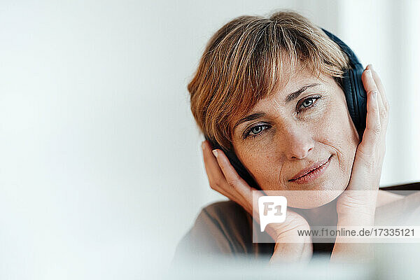 Businesswoman staring while listening music through headphones in office