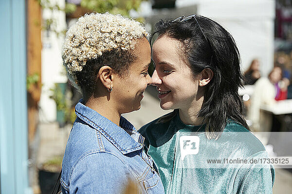 Lesbian couple smiling while looking at each other on sunny day