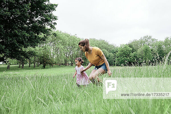 Mother and daughter running on grass in park