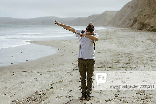 Young man dabbing while standing at beach at Point Reyes  California  USA
