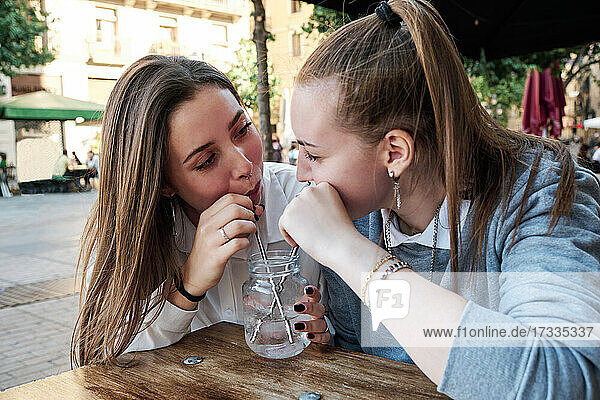 Young lesbian couple having drink together at sidewalk cafe