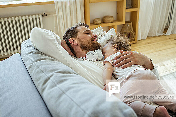 Mann mit Tochter schläft auf dem Sofa zu Hause