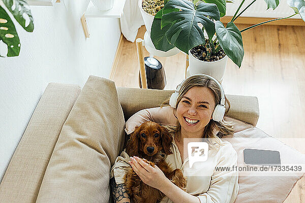 Happy woman with Cocker Spaniel relaxing on sofa in living room