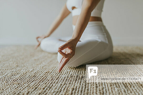 Weibliche Fitness-Trainerin meditiert auf dem Teppich im Yoga-Studio
