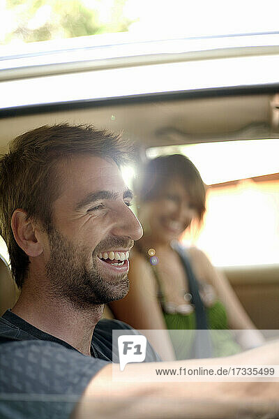 Glücklicher junger Mann mit Freundin im Auto während einer Autoreise