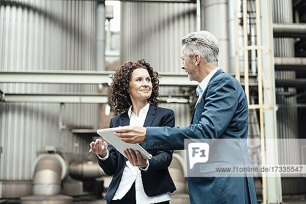 Businesswoman using digital tablet while discussing with colleague in front of industrial building