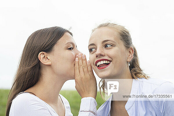 Blond woman looking away while listening to female friend gossiping