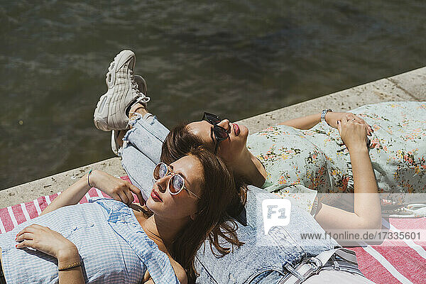 Freundinnen entspannen sich auf dem Schoß eines Mannes am Fluss
