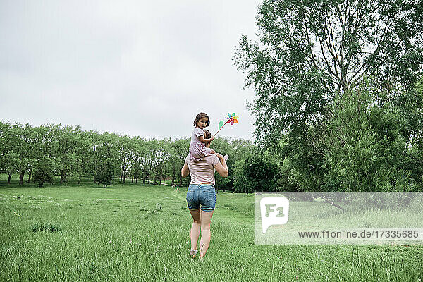 Mutter trägt Tochter auf den Schultern beim Spaziergang im Park