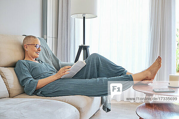 Frau liest ein Buch und entspannt sich auf dem Sofa zu Hause