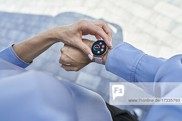 Geschäftsfrau prüft smarte Armbanduhr  während sie auf dem Fußweg steht