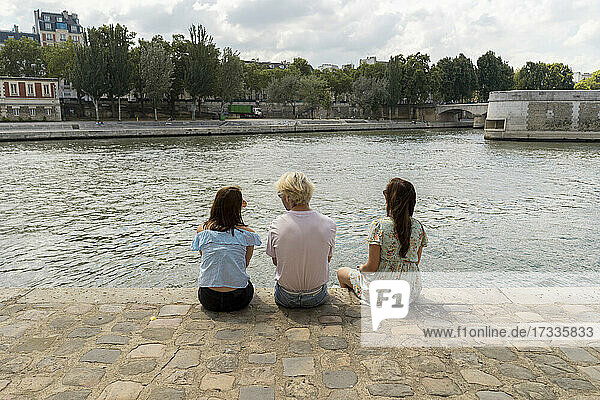 Männliche und weibliche Freunde sitzen in den Ferien am Fluss