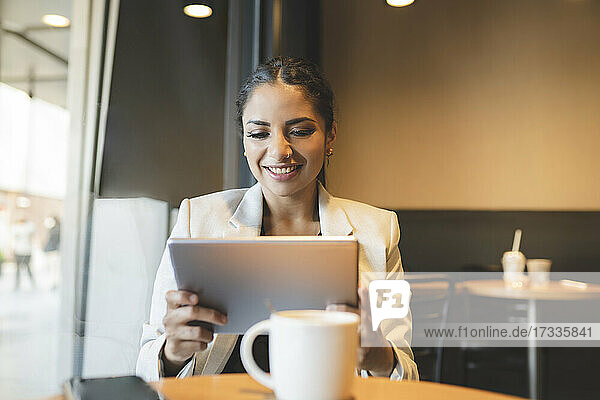 Weibliche Fachkraft  die im Café sitzend ein digitales Tablet benutzt