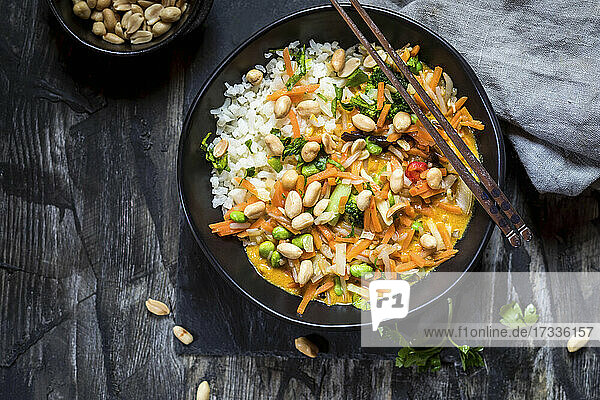 Erdnüsse garniert mit gelbem Blumenkohl und Thaicurry-Reis auf dem Tisch