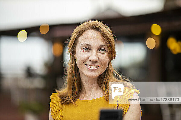 Lächelnde rothaarige Frau mit Mobiltelefon