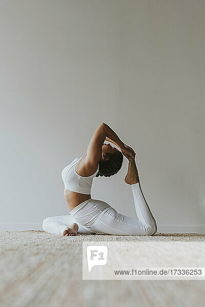 Flexibler Yogi übt Yoga an der Wand im Studio