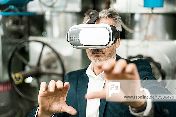 Geschäftsmann gestikuliert bei der Verwendung eines Virtual-Reality-Headsets in einem Workshop