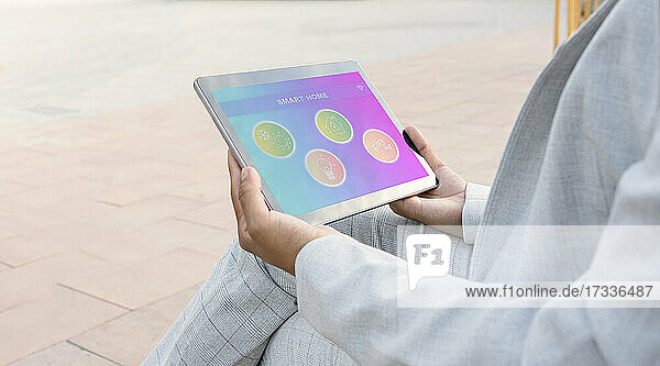 Geschäftsfrau  die auf dem Gehweg sitzend ein Smart Home Tablet benutzt