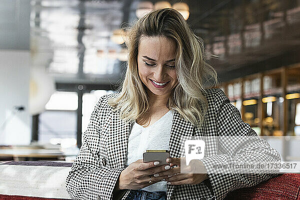 Lächelnde Geschäftsfrau mit Mobiltelefon in einem Café