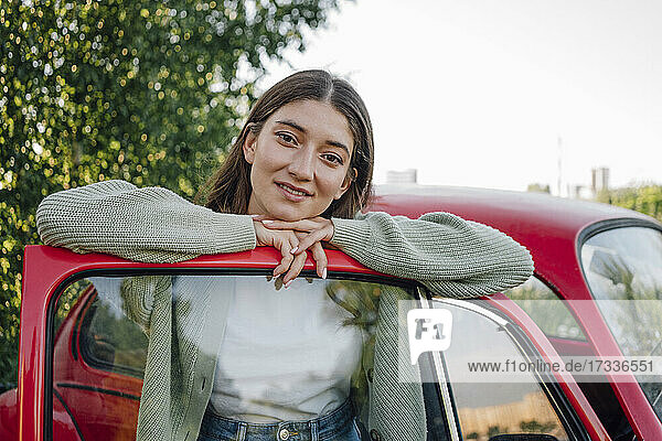 Beautiful young woman leaning on car door