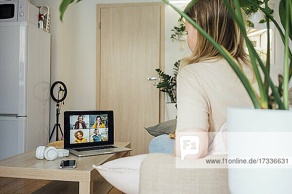 Geschäftsfrau im Gespräch mit Kollegen während einer Videokonferenz über einen Laptop zu Hause