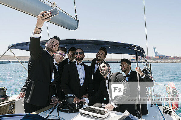Mann nimmt Selfie mit männlichen Freunden durch Handy in Jacht
