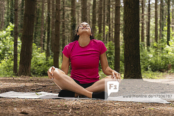 Young woman doing relaxation exercise while sitting in forest