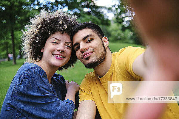 Smiling curly haired woman sitting with boyfriend at park