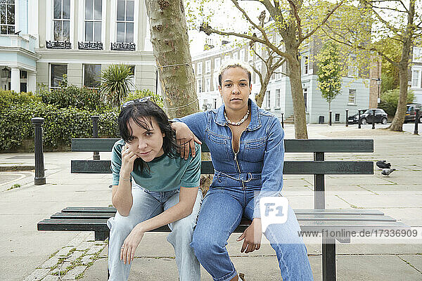 Lesbisches Paar  das auf einer Bank in der Stadt sitzt und sich anstarrt
