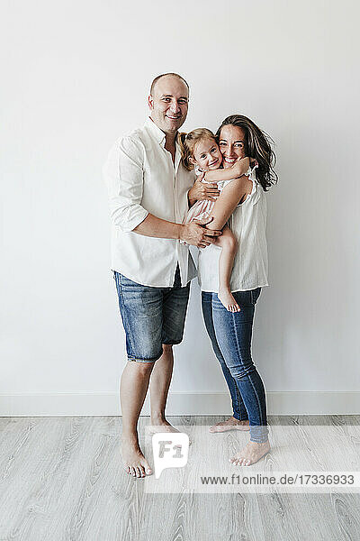 Happy family standing in front of white wall at home