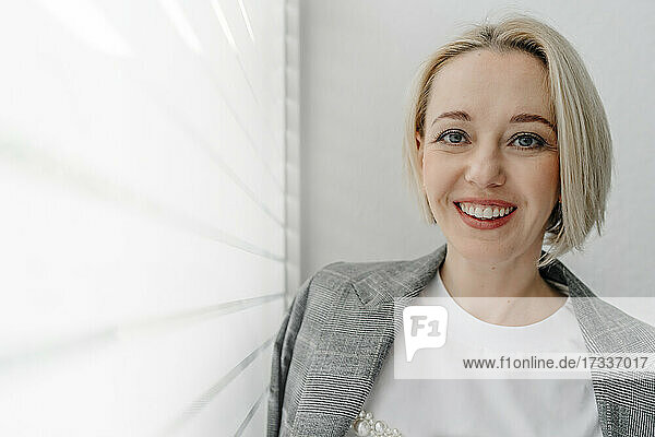 Schöne lächelnde reife Geschäftsfrau steht am Fenster im Büro