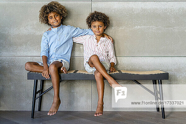 Afro brothers with hand on shoulders sitting on bench