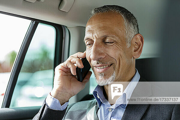 Businessman talking on smart phone in car