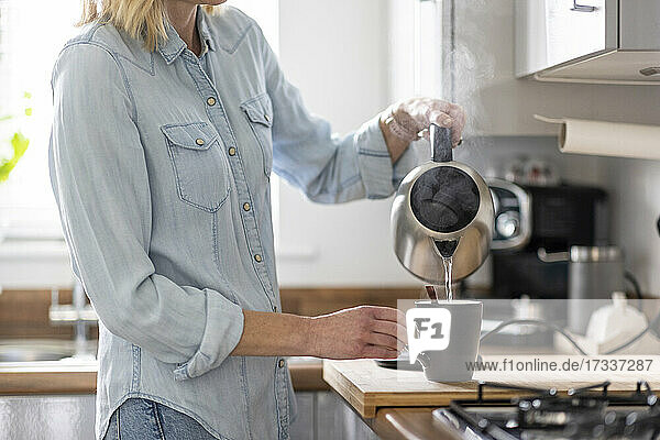 Frau bei der Zubereitung von Tee in der Küche zu Hause
