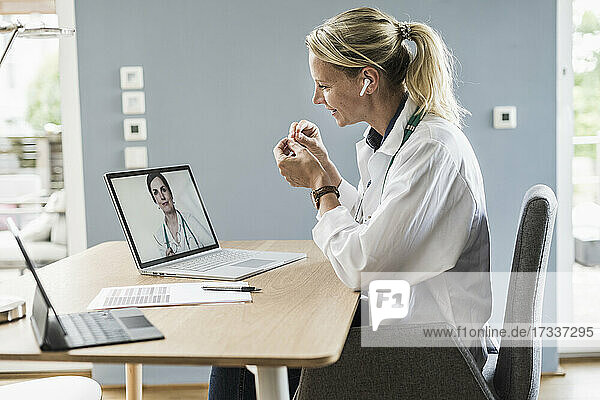 Weibliche Fachkraft gestikuliert  während sie mit einem Kollegen über einen Videoanruf am Laptop im Büro diskutiert
