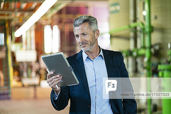 Männlicher Fachmann  der ein digitales Tablet benutzt  während er in einem Kraftwerk steht