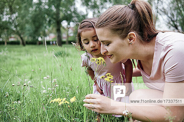 Mutter und Tochter riechen im Park an Blumen