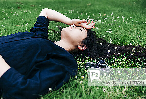 Young female photographer with old-fashioned camera resting on grass