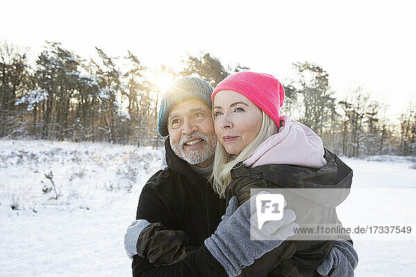 Senior couple in warm clothing embracing each other during winter