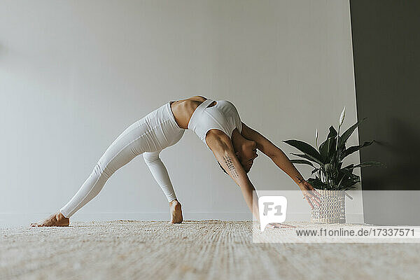 Flexibler Yogi beim Üben  während er sich im Yogastudio nach hinten beugt
