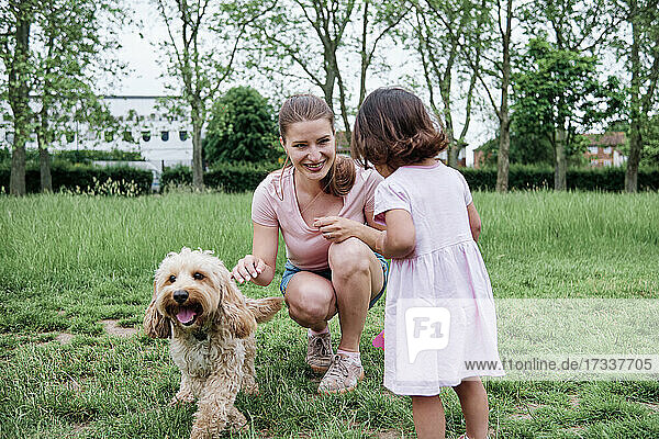 Mutter und Tochter spielen mit Hund im Park