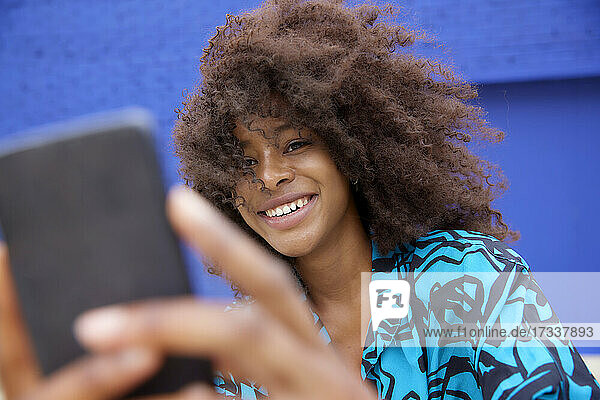 Smiling woman taking selfie through smart phone