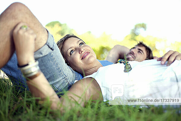 Männliche und weibliche Freunde entspannen sich im Gras eines öffentlichen Parks