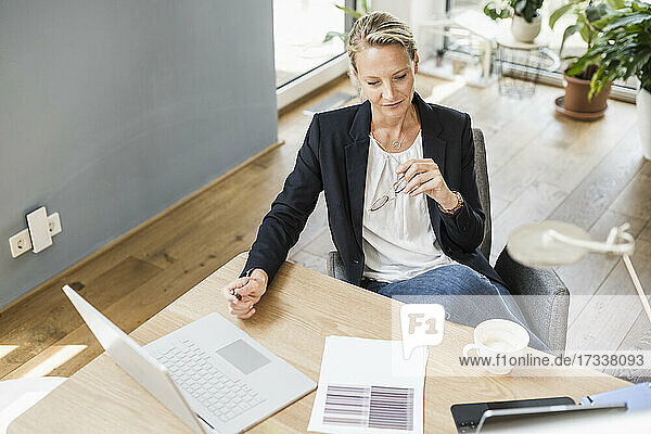 Businesswoman with laptop and digital tablet sitting at office