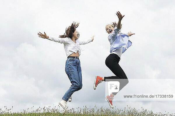 Carefree young female friends jumping on grass