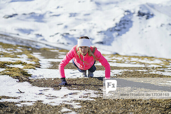 Weibliche Athletin macht Liegestütze auf einem Berg an einem sonnigen Tag