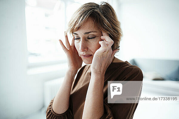 Reife Geschäftsfrau mit Kopfschmerzen im Büro