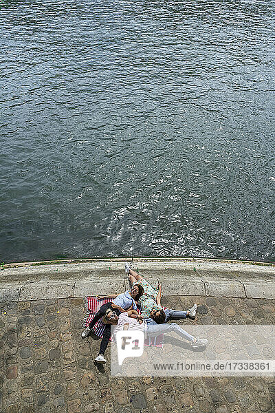 Männliche und weibliche Freunde liegen auf der Promenade am Fluss