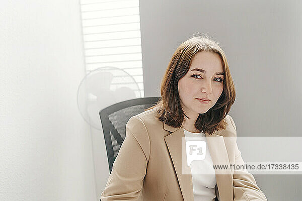 Junge Geschäftsfrau mit braunen Haaren sitzt im Büro