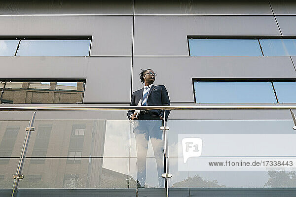 Businessman holding laptop while standing at office building